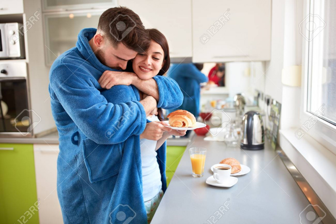 Young Happy Couple Hugging In Kitchen In The Morning Stock Photo