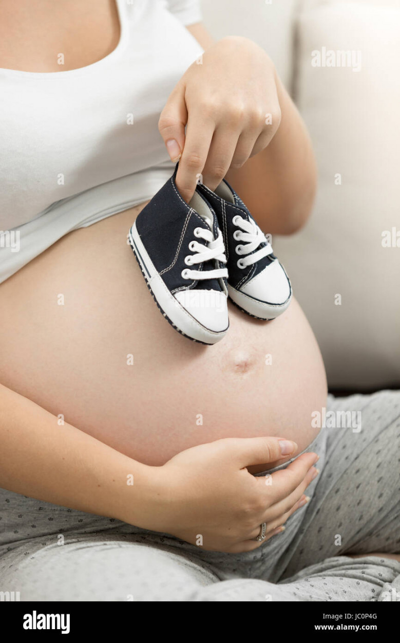 Pregnant woman holding baby boy shoes on belly Stock Photo - Alamy